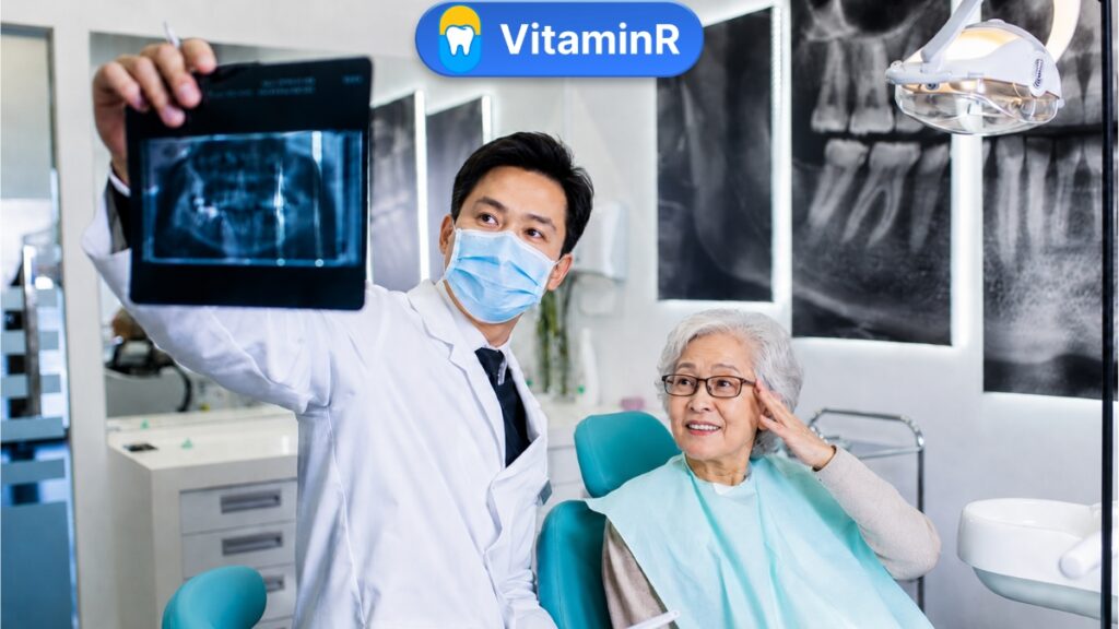 Bác sĩ tư vấn trồng răng Implant cho bệnh nhân lớn tuổi bị loãng xương sau khi xem phim X-quang răng hàm tại nha khoa vitaminr