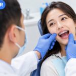 Bác sĩ kiểm tra răng đang đeo mắc cài, tư vấn niềng răng có hại không